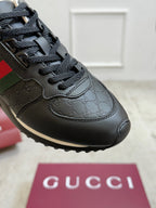 Gucci unisex sneaker close-up, black upper with embossed GG pattern and black laces