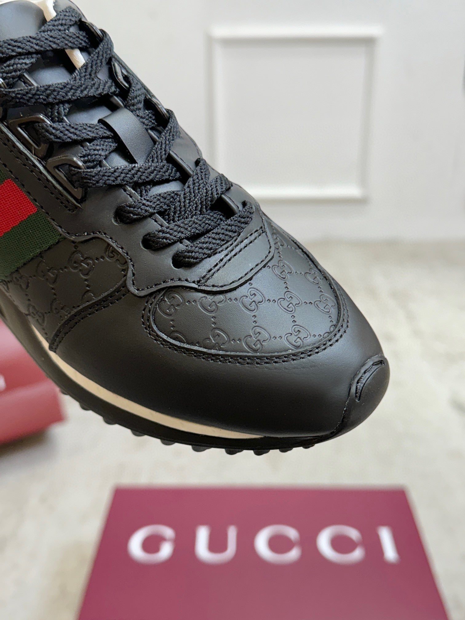 Gucci unisex sneaker close-up, black upper with embossed GG pattern and black laces