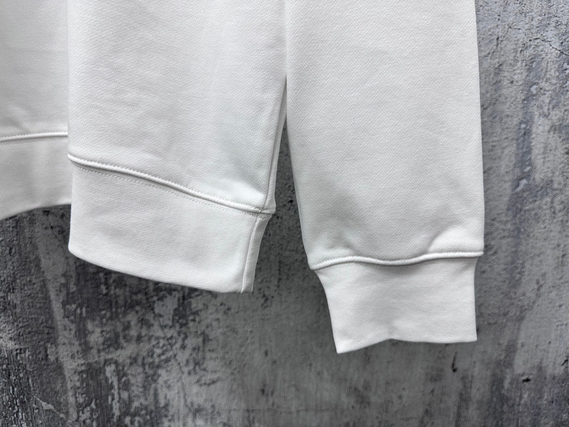 White sweatshirt hem and sleeve cuffs, showing relaxed fit and stitching