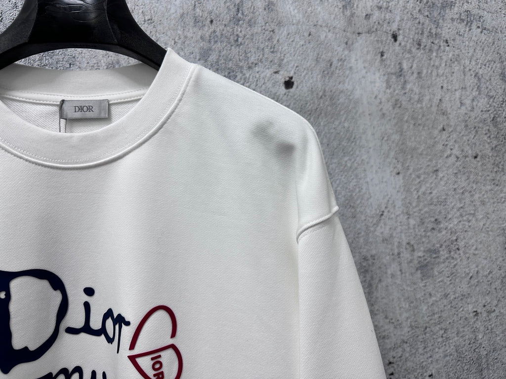 White sweatshirt neckline close-up with Dior tag and partial logo graphic