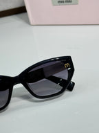 Black sunglasses close-up with dark lenses beside pink logo case