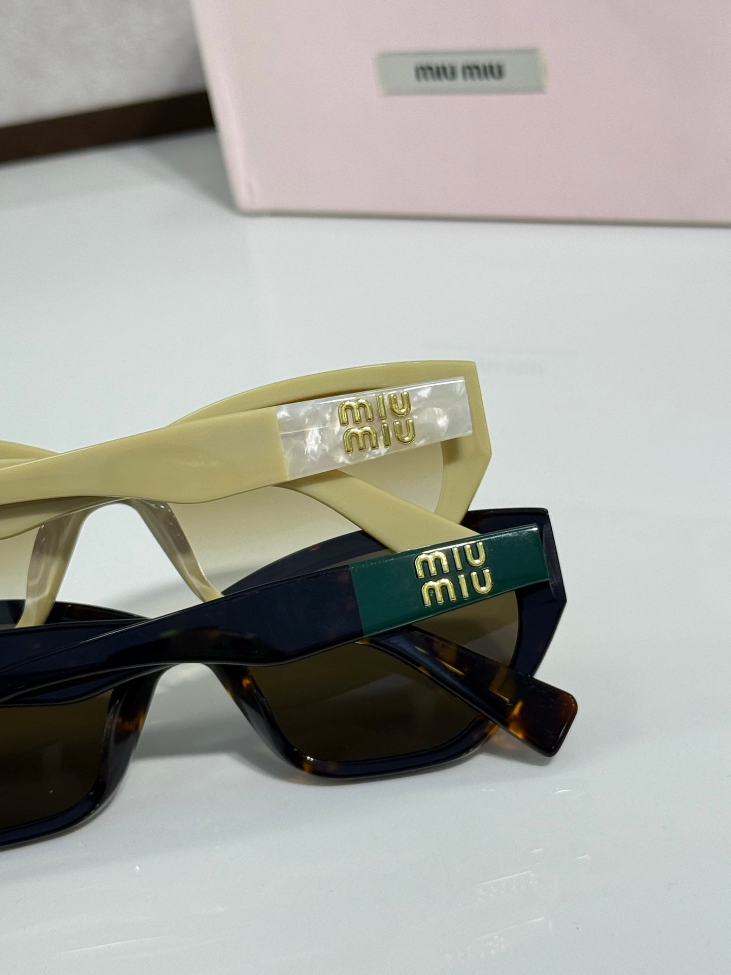 Olive and black sunglasses close-up with branded temple and logo case