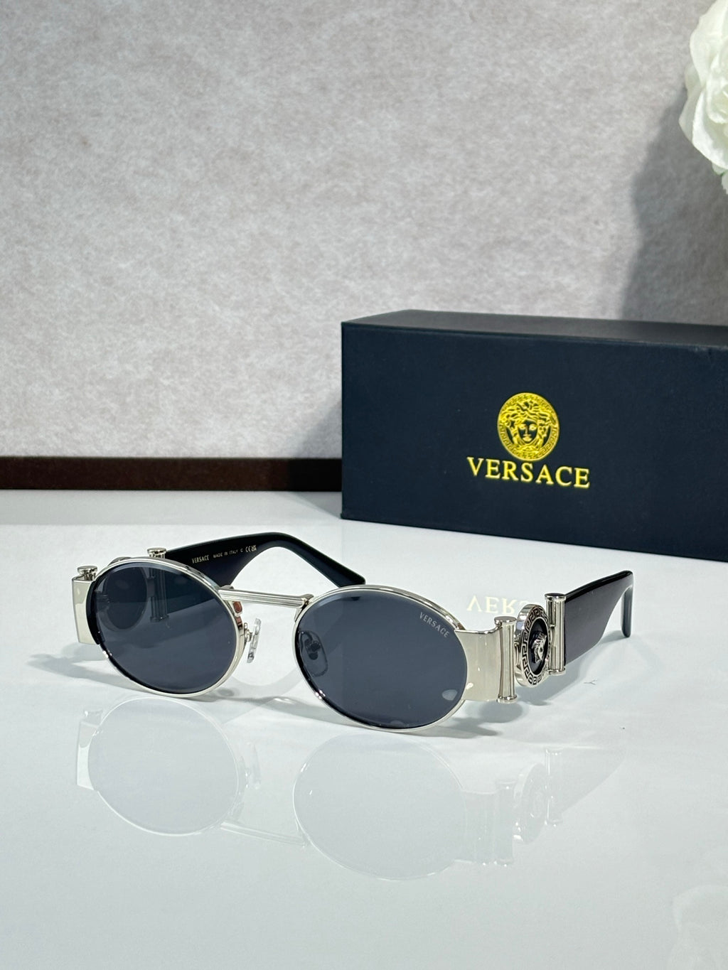 Versace sunglasses with round lenses, silver frame and dark blue tinted lenses.