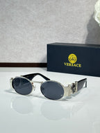 Versace sunglasses with round lenses, silver frame and dark blue tinted lenses.