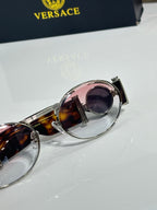 Versace sunglasses close-up of pink-lensed round frames with tortoiseshell accents.