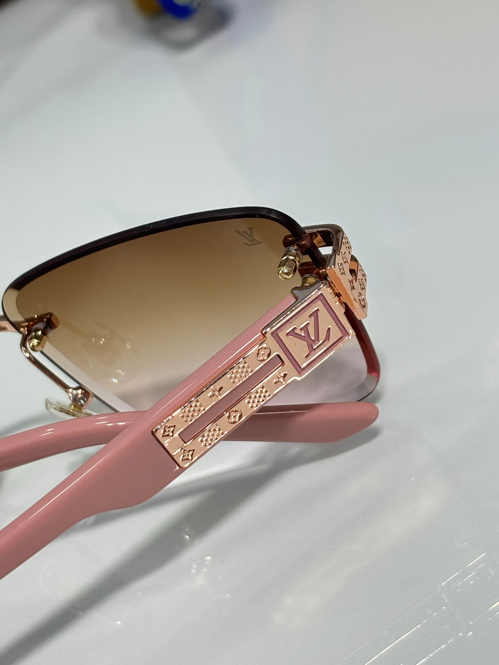 Louis Vuitton sunglasses close-up with pink frame and LV logo detail