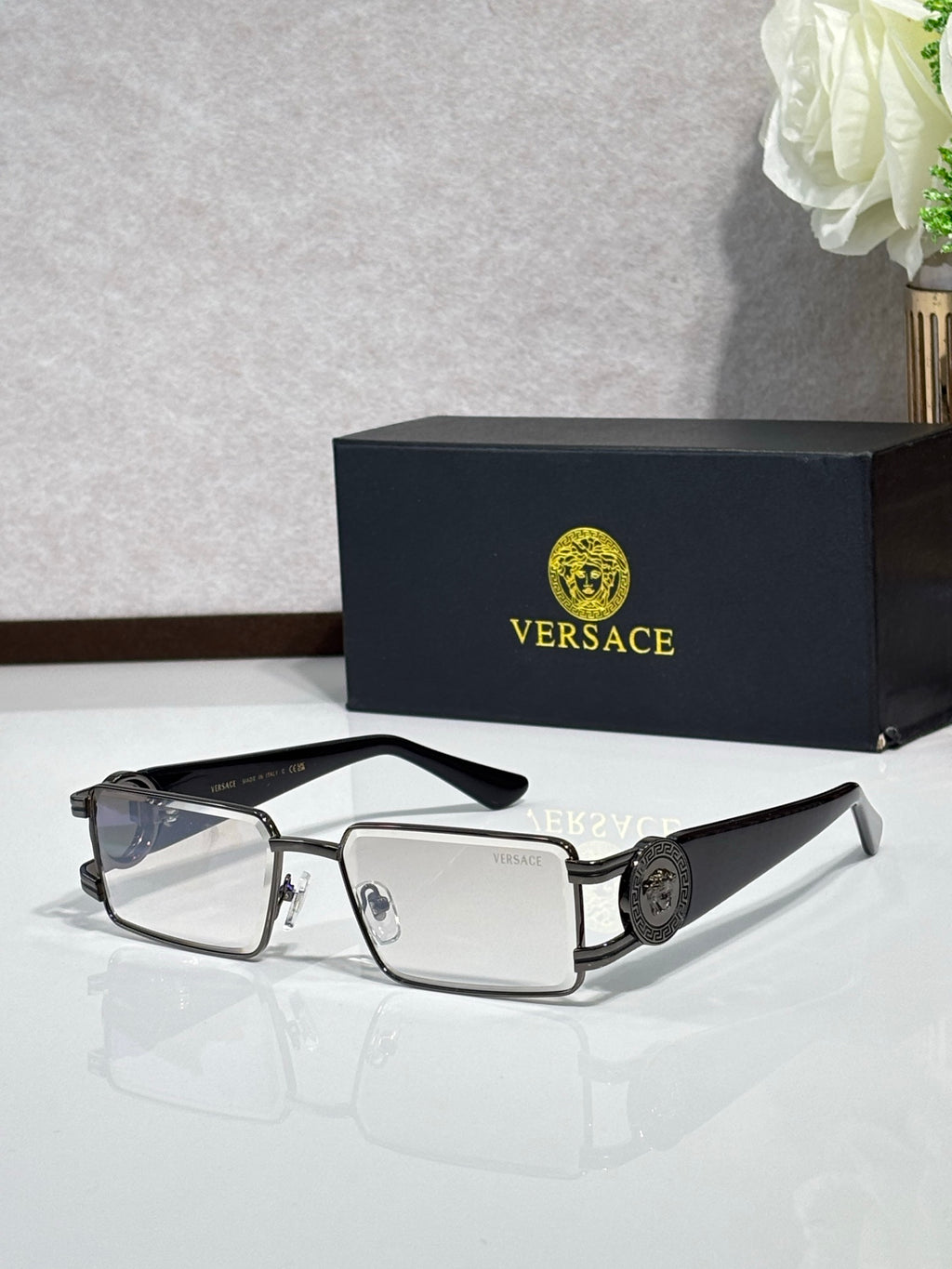 Silver-tone rectangular eyeglasses with clear lenses and logo medallion on the temple