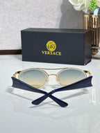 Gold round sunglasses with light-reflective lenses and dark temple tips, laid on a glossy surface.