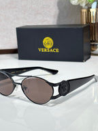 Black round sunglasses with dark lenses and a circular medallion on the temple, mirrored finish.
