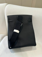 Hermes pebbled leather flap bag back view with adjustable strap and dark pocket detail