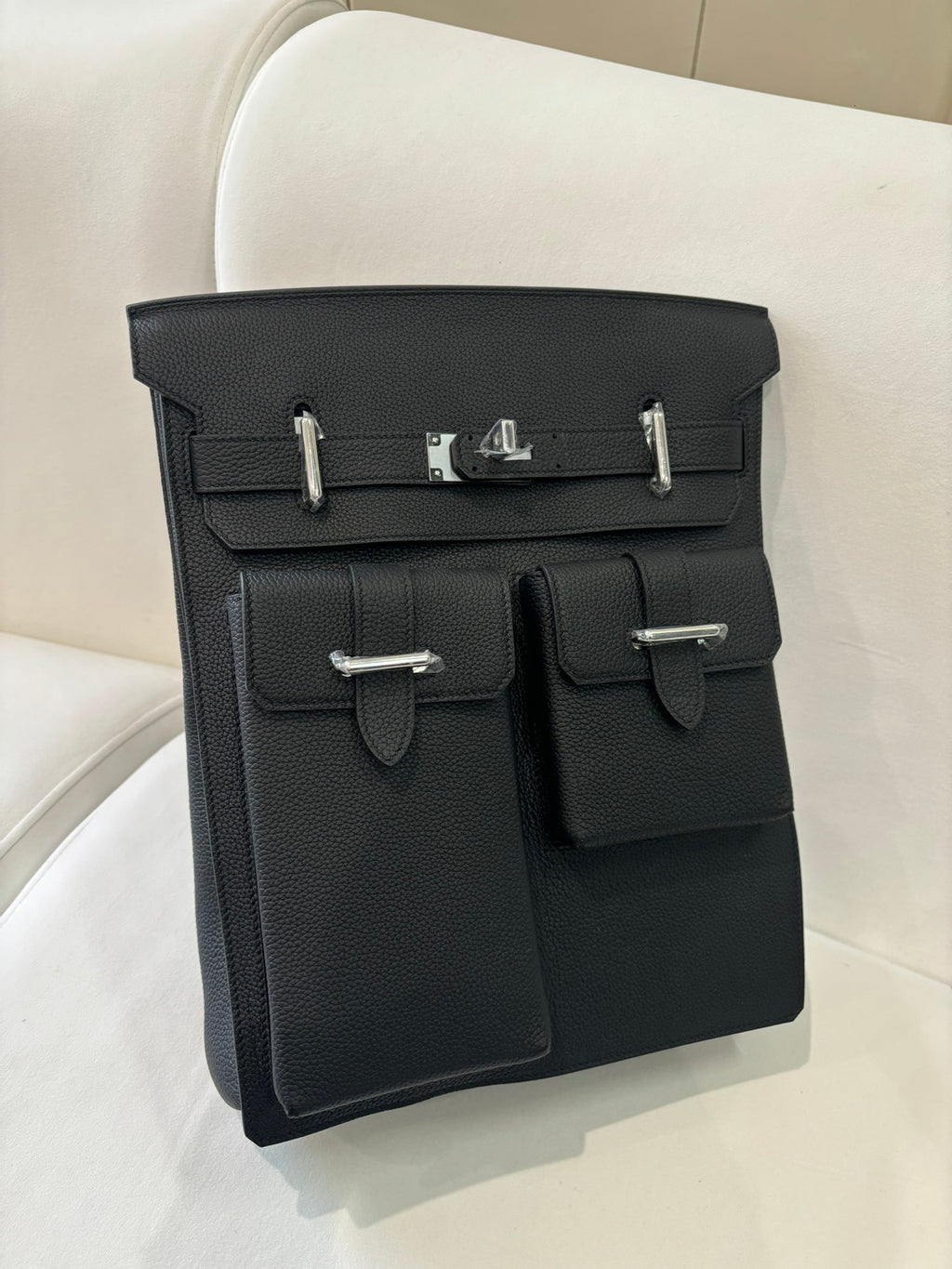 Hermes pebbled leather flap bag angled view with silver hardware and two front pockets