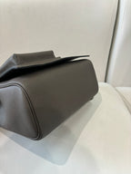 Hermes leather handbag gray angled view with flap top and side seam paneling
