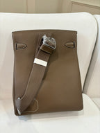Hermes bag in taupe leather with front flap and shoulder strap detail, rear view