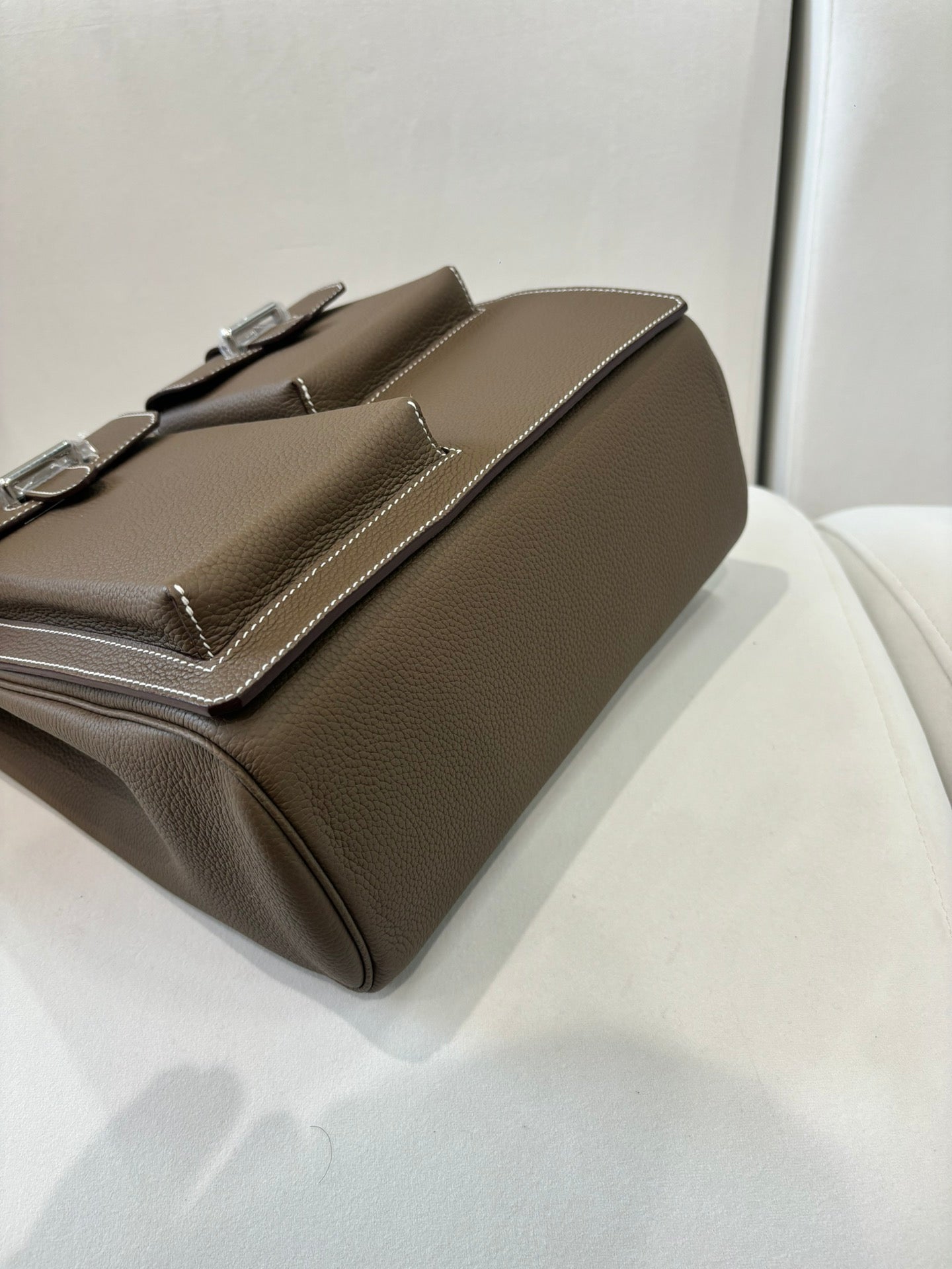 Hermes bag in taupe leather, angled side view with flap and structured body