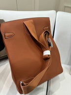 Hermes bag tan brown leather with adjustable shoulder strap and top handle, side view.
