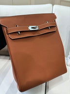 Hermes bag front view in tan brown leather with stitched flap, silver clasp, and side straps.