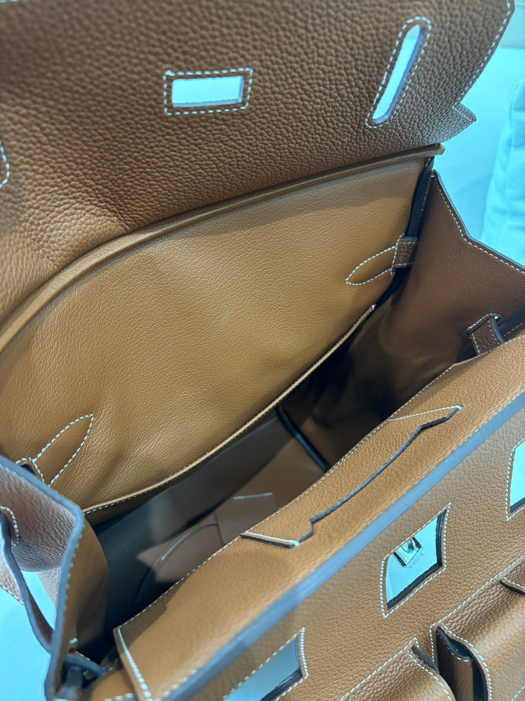 Hermes bag interior lining with tan compartments and blue accents near the top opening.