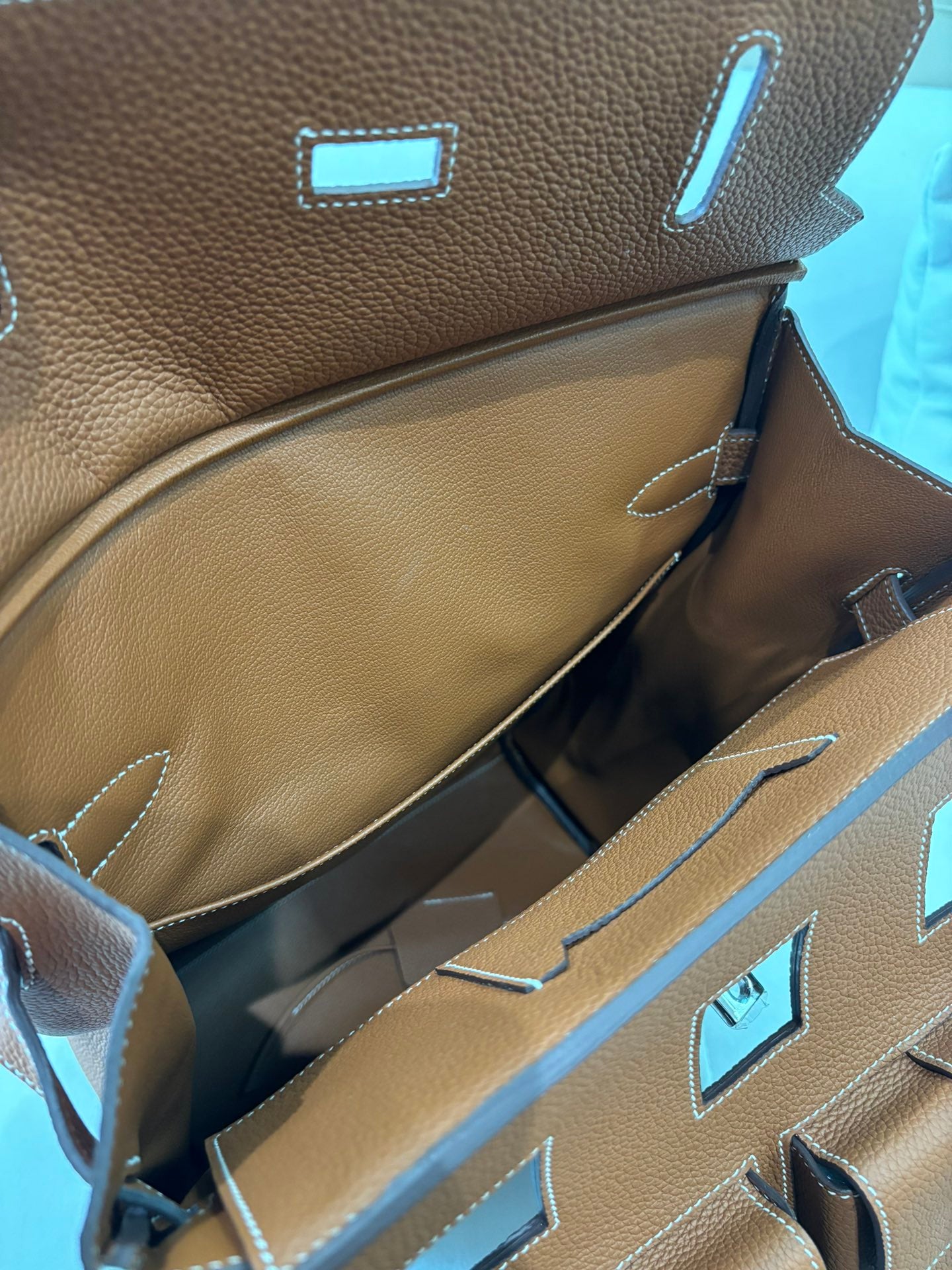 Hermes bag interior lining with tan compartments and blue accents near the top opening.