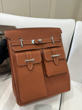 Hermes bag in tan brown leather with front flap and silver buckle hardware, square shape.