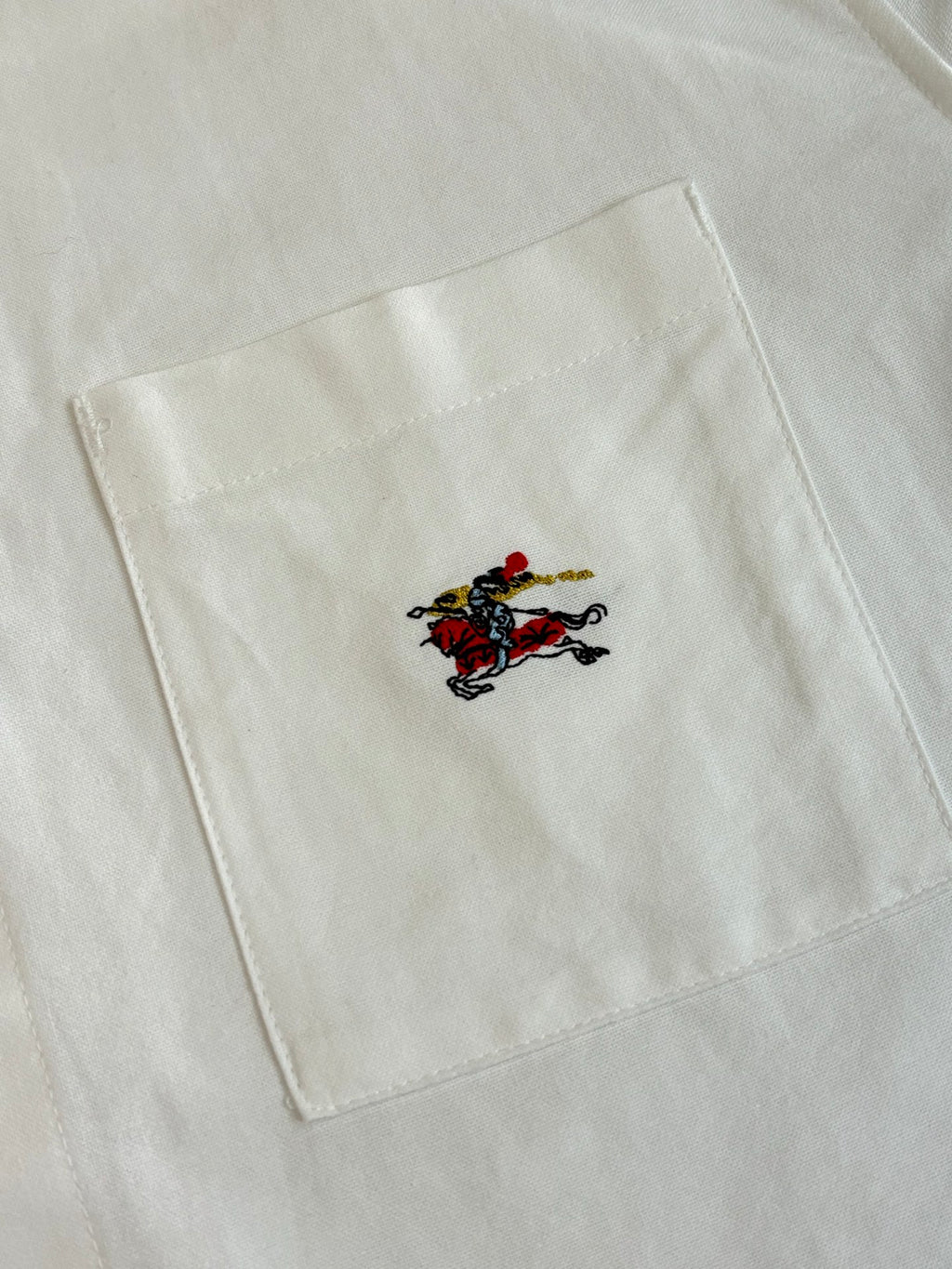 White shirt fabric with embroidered horse logo near the chest