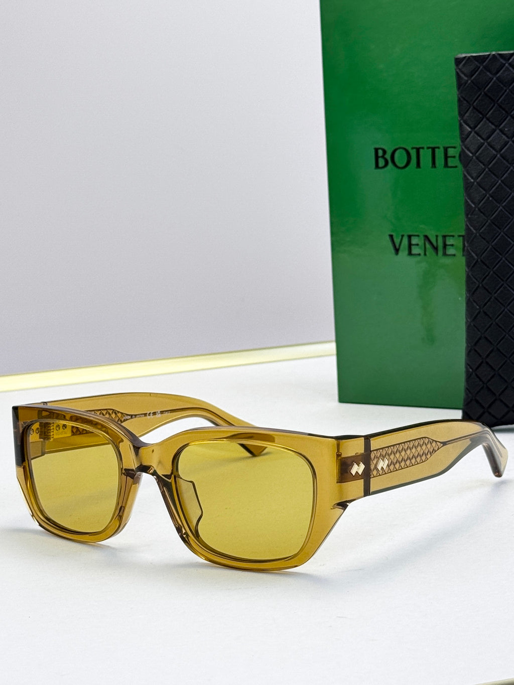 Bottega Veneta sunglasses with gold frames, amber lenses, and gold patterned temples