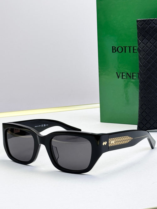 Bottega Veneta sunglasses with black frames, dark gray lenses, and gold patterned temples