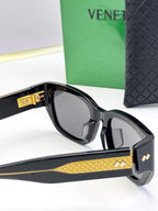Bottega Veneta sunglasses with black frames, gold patterned temple, and gold logo accent