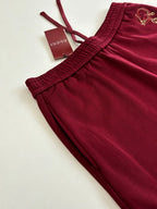 Burgundy pants laid flat, ribbed elastic waistband and drawstring ends