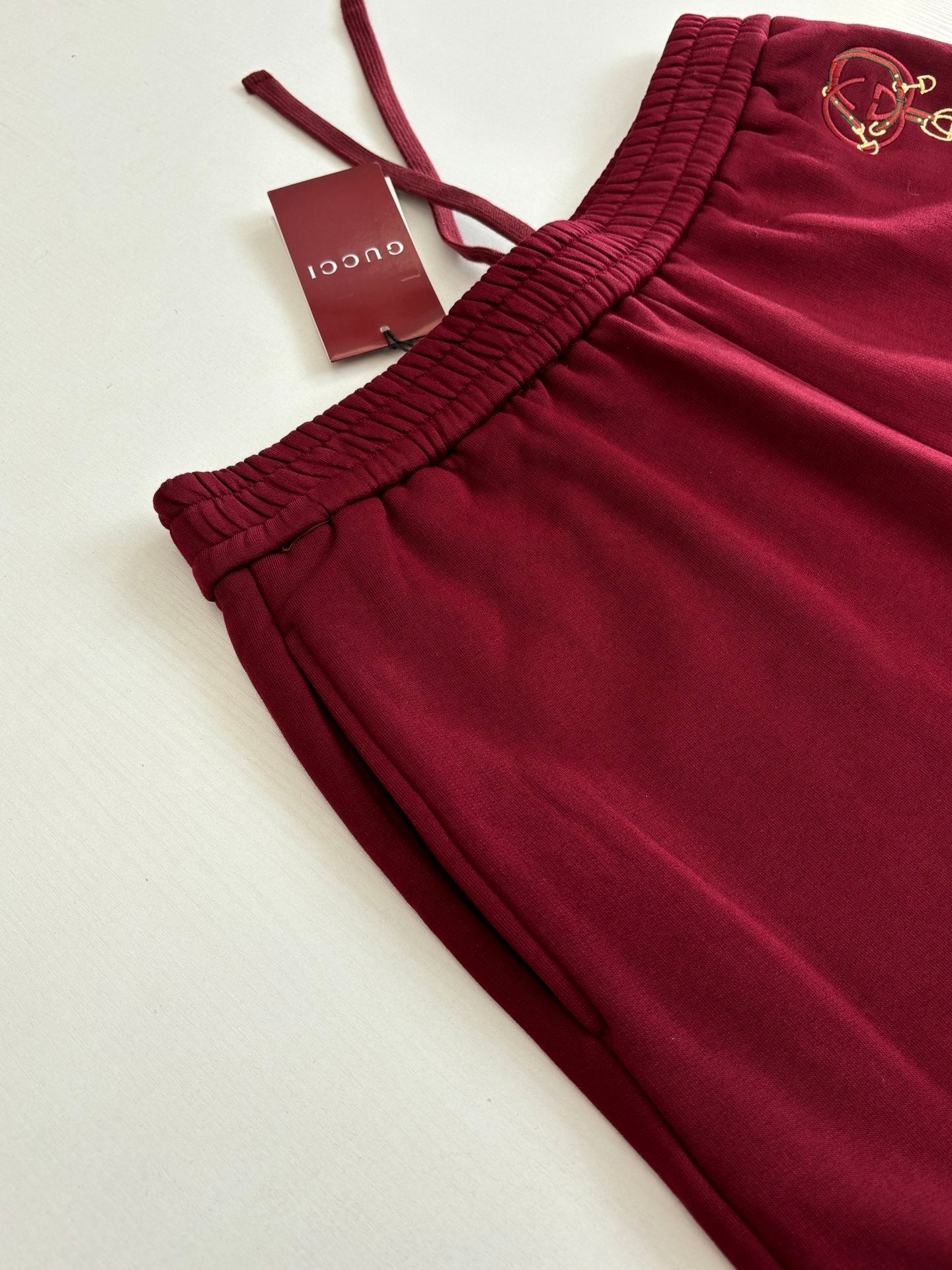 Burgundy pants laid flat, ribbed elastic waistband and drawstring ends