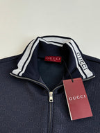 Navy Gucci track jacket collar with white striped trim and logo tag