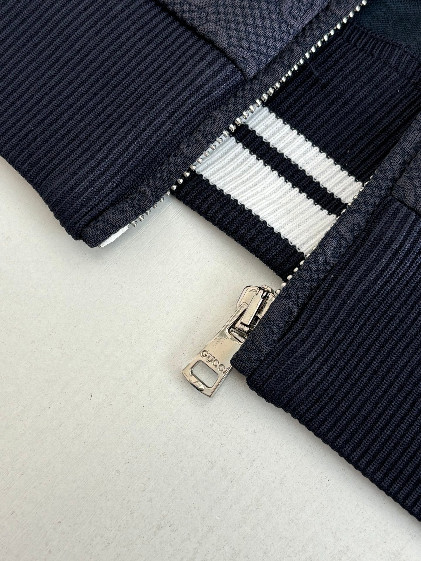 Navy Gucci track jacket zipper pull with white striped knit trim