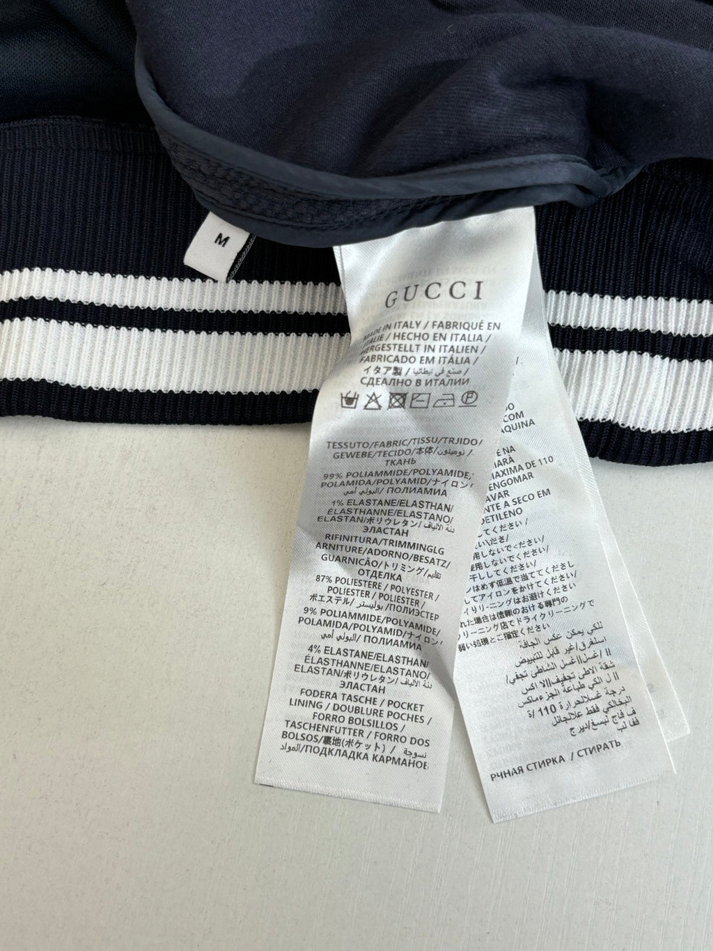 Dark knit garment with ribbed cuff and white Gucci care labels