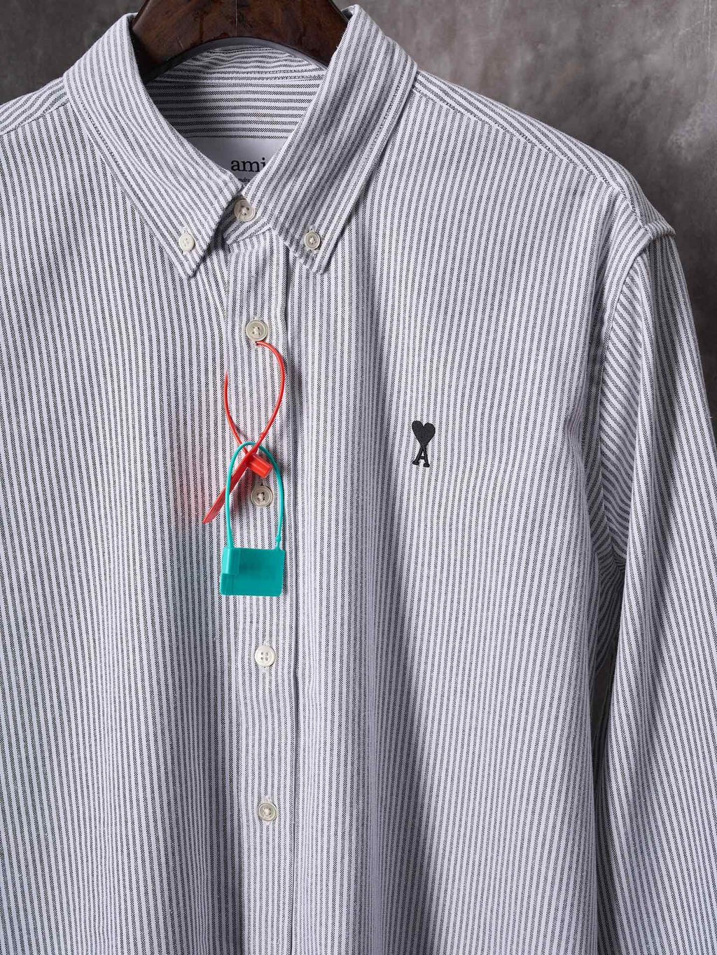Striped button-up shirt with black chest emblem and multicolor hanging tag