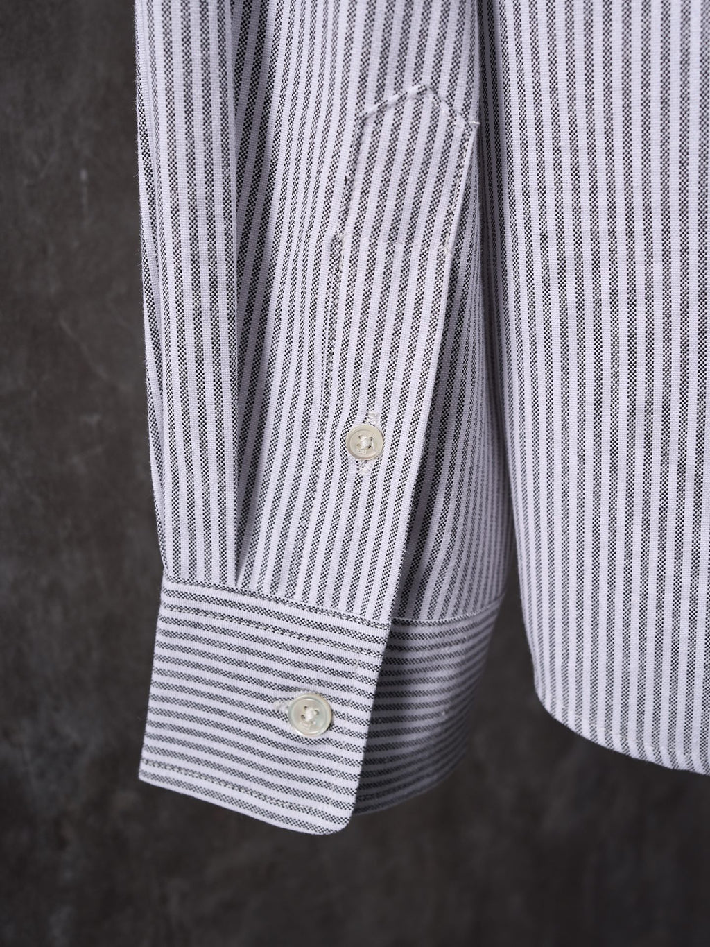 Striped button-up shirt cuff with button in light blue and white stripes
