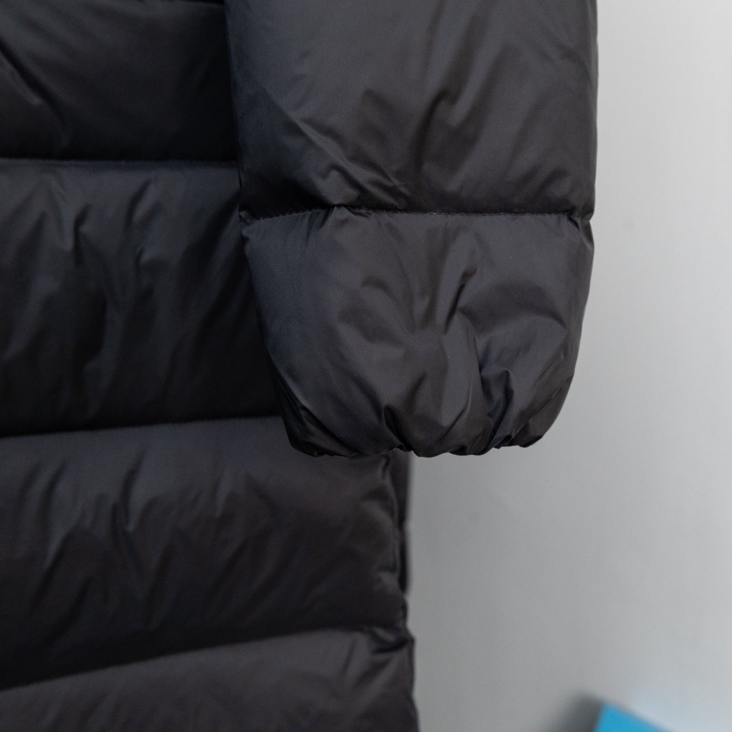 Long puffer jacket quilted sleeve with elastic cuff, dark fabric.