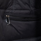 Long puffer jacket front zipper and ribbed storm flap, dark outer fabric.