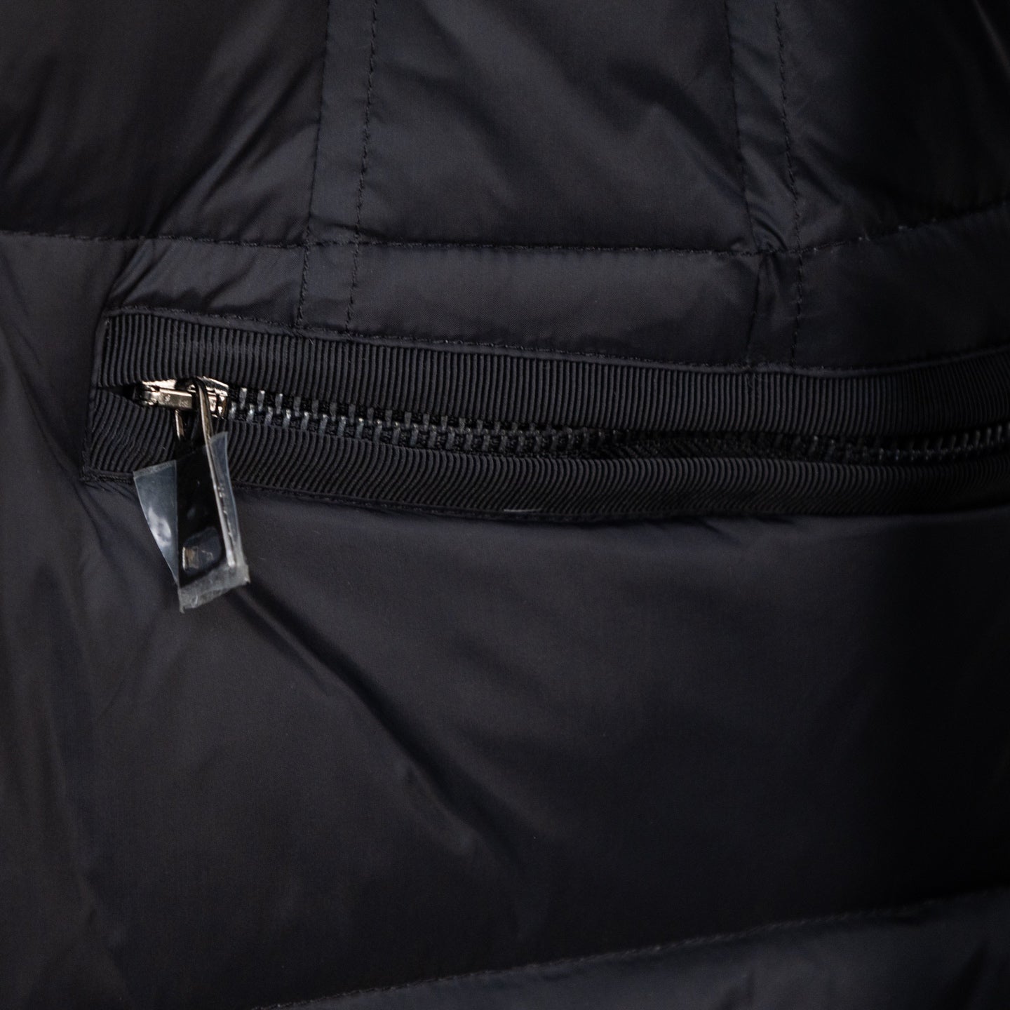 Long puffer jacket front zipper and ribbed storm flap, dark outer fabric.