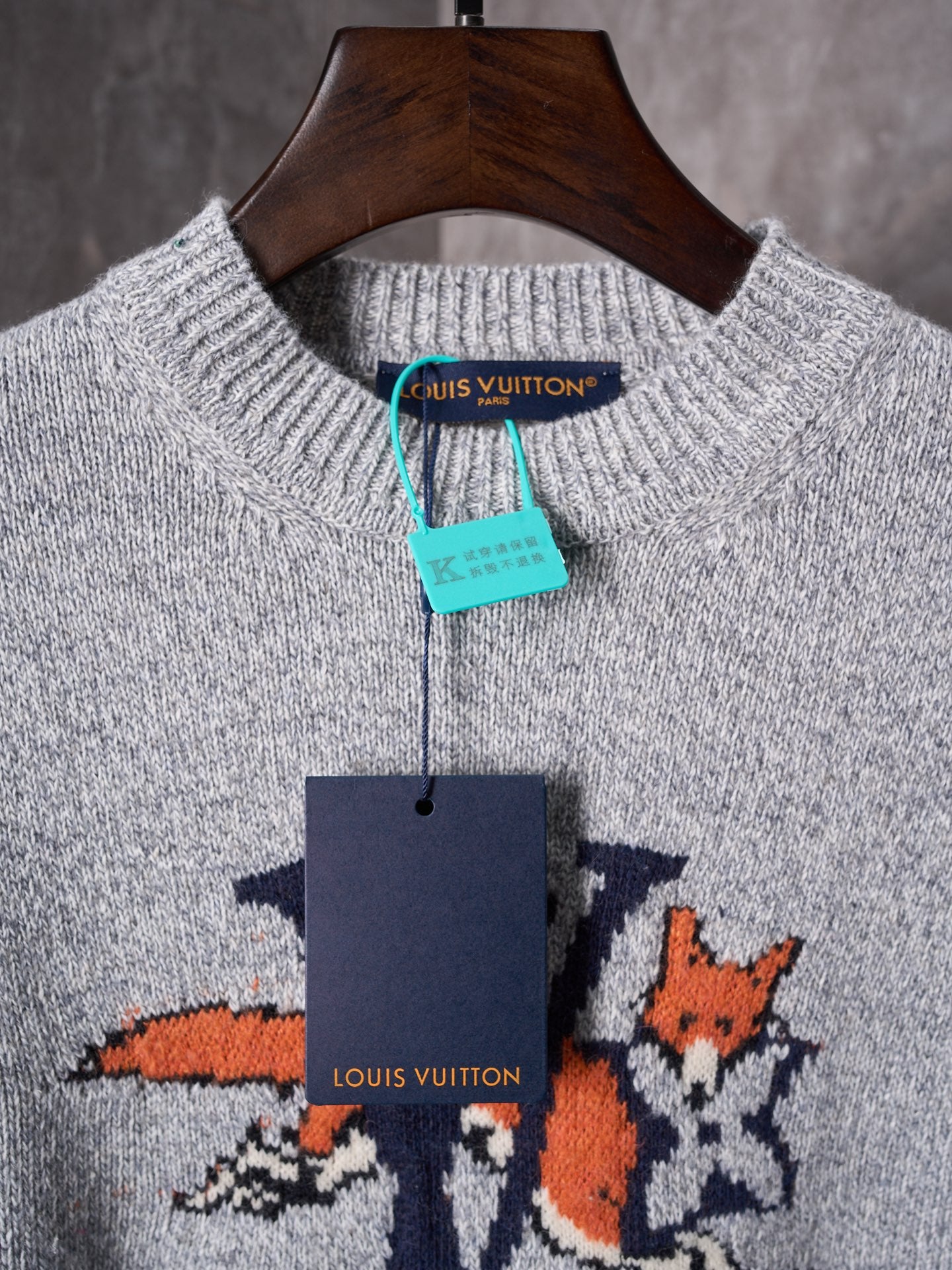 Light gray knit sweater with crew neck and multicolor graphic; brand tags visible