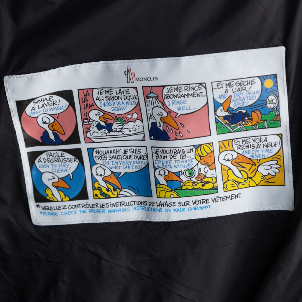 Long puffer jacket care label panel with Moncler name and washing icons.