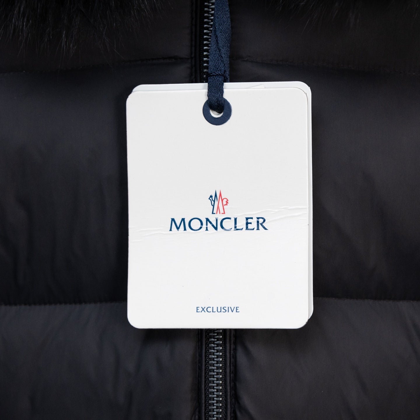 Moncler garment tag on long puffer coat zipper, dark fabric