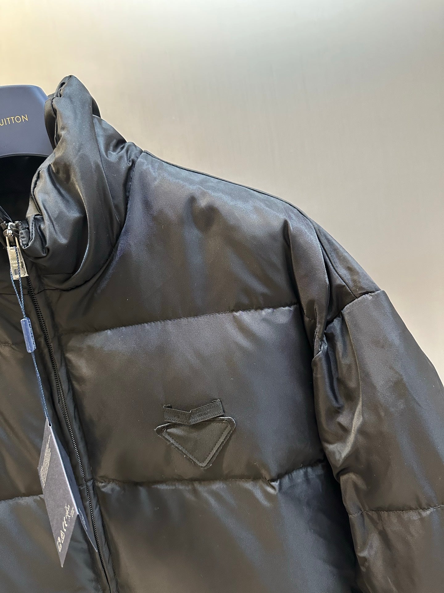 Prada dark puffer jacket side profile with quilted panels and zipper