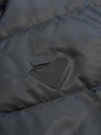 Prada dark puffer jacket close-up of embroidered triangle chest logo