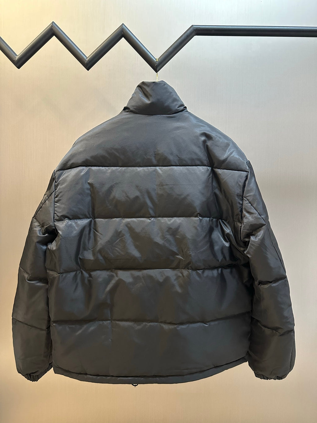 Prada dark puffer jacket back view with horizontal quilting and padded shoulders