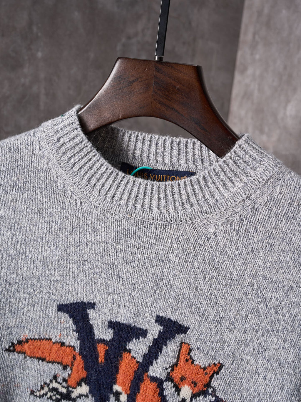 Light gray crewneck knit sweater close-up with ribbed collar and multicolor graphic