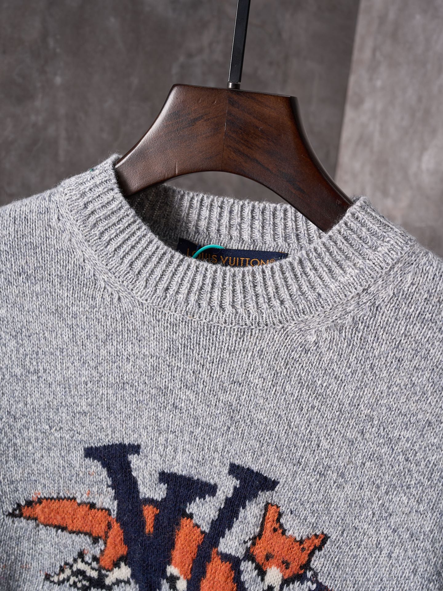 Light gray crewneck knit sweater close-up with ribbed collar and multicolor graphic