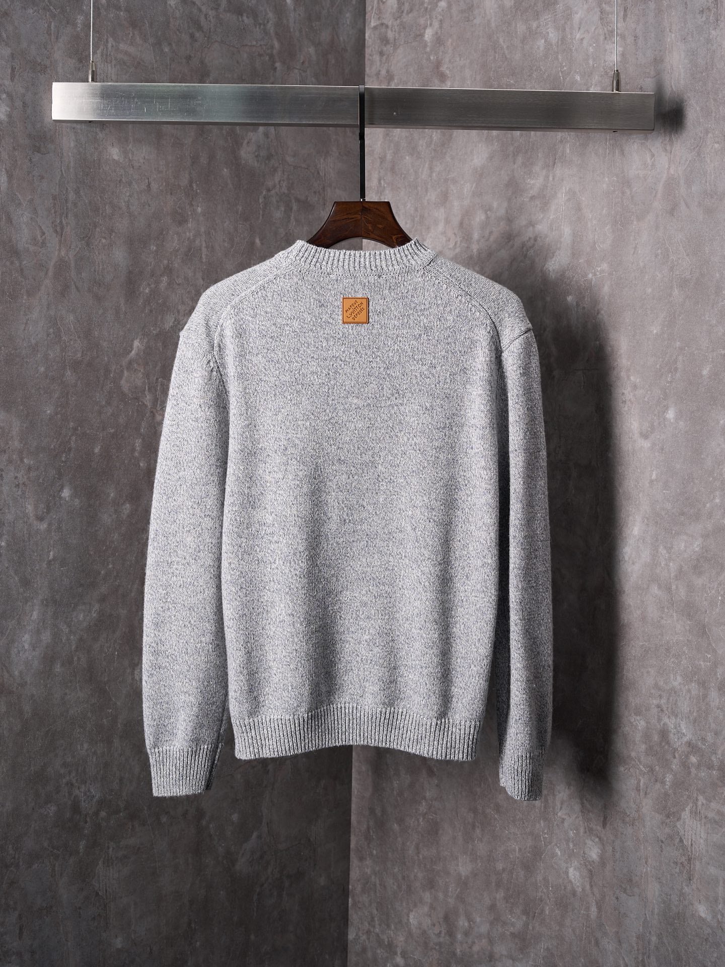 Light gray knit sweater with crew neck; small square chest logo patch