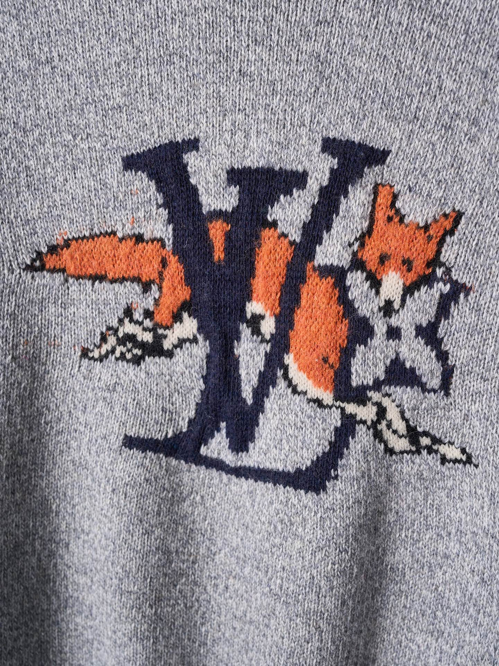 Light gray knit sweater close-up featuring multicolor graphic letter and character design