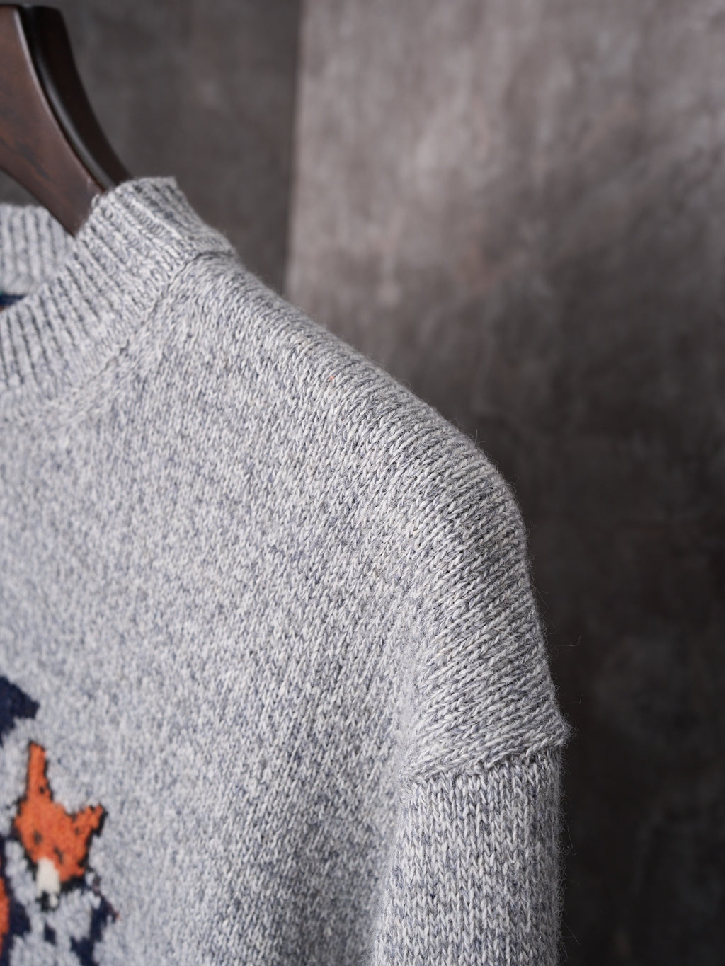Light gray knit sweater shoulder and sleeve close-up with ribbed collar detail