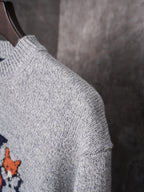 Light gray knit sweater shoulder and sleeve close-up with ribbed collar detail