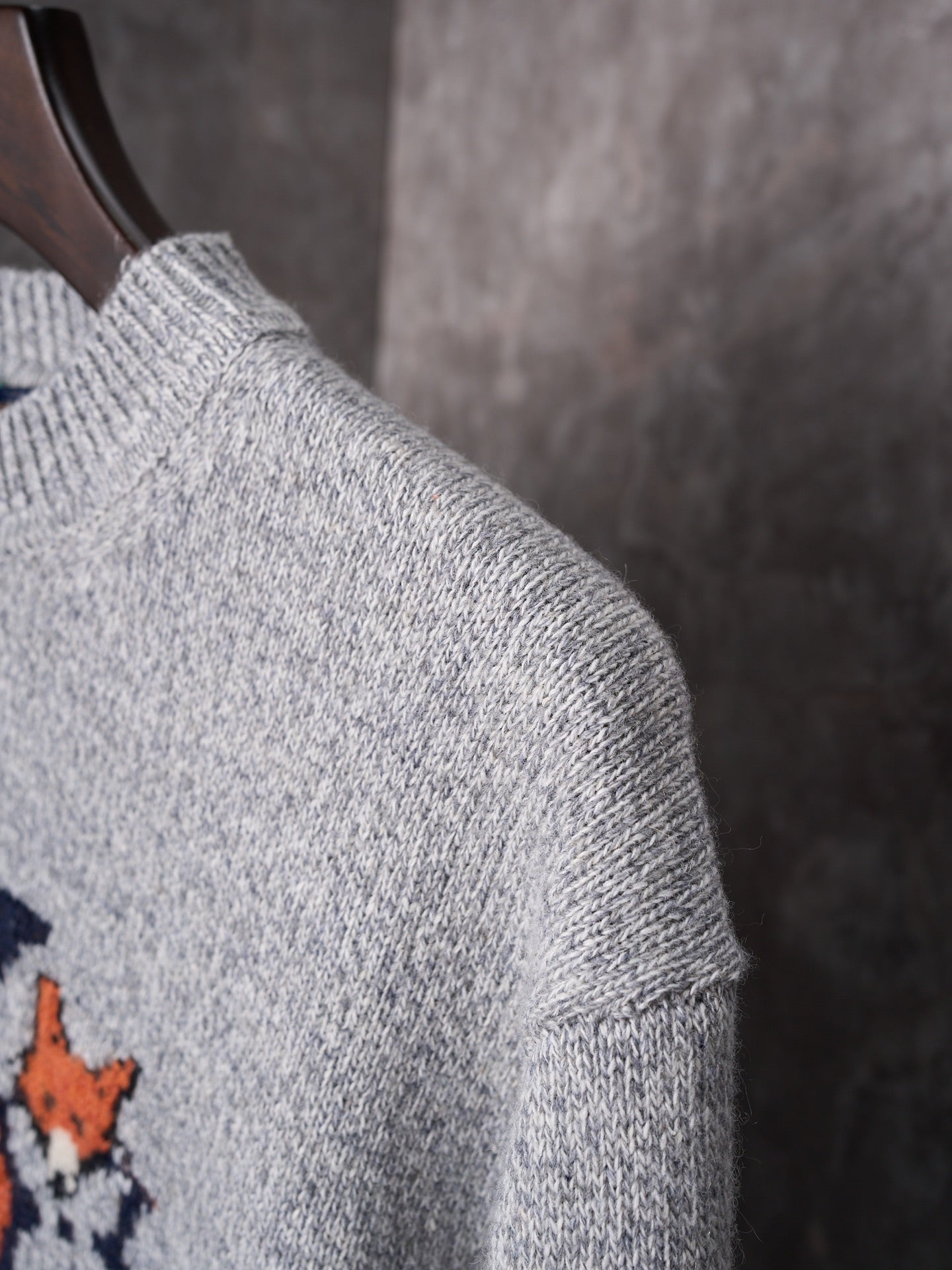Light gray knit sweater shoulder and sleeve close-up with ribbed collar detail